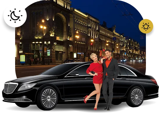 Formal couple posing next to a black luxury sedan against a backdrop of historic city architecture lit up at night.